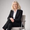 W025   A professional woman in a black pantsuit sitting on a modern chair